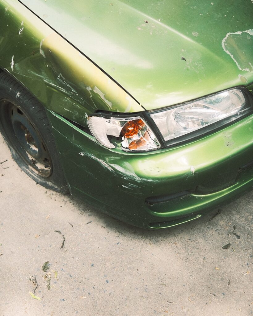 a green car with a dented front bumper
