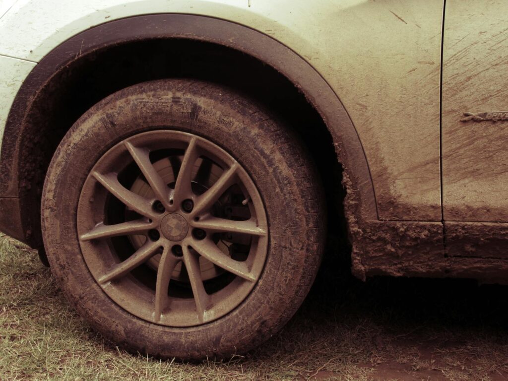 Is a Monthly Car Wash Membership Worth It? 4 Close-up view of a car wheel covered in mud, highlighting off-road adventures.