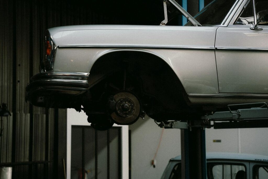 The Undercarriage of a Car: Why It Matters and How to Protect It 1 A classic car is elevated on a lift in a professional auto repair garage, showcasing its undercarriage.