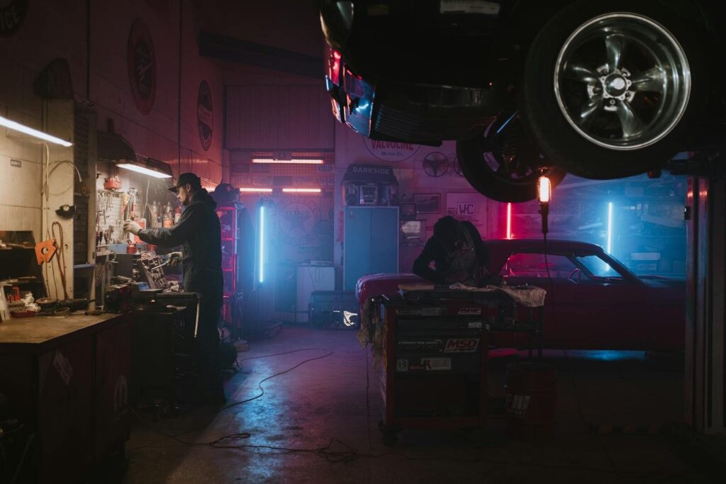 Why An Undercarriage Car Wash is Essential for Your Vehicle's Health 1 Mechanics working in a neon-lit garage, focusing on tools and car repairs under vibrant lights.