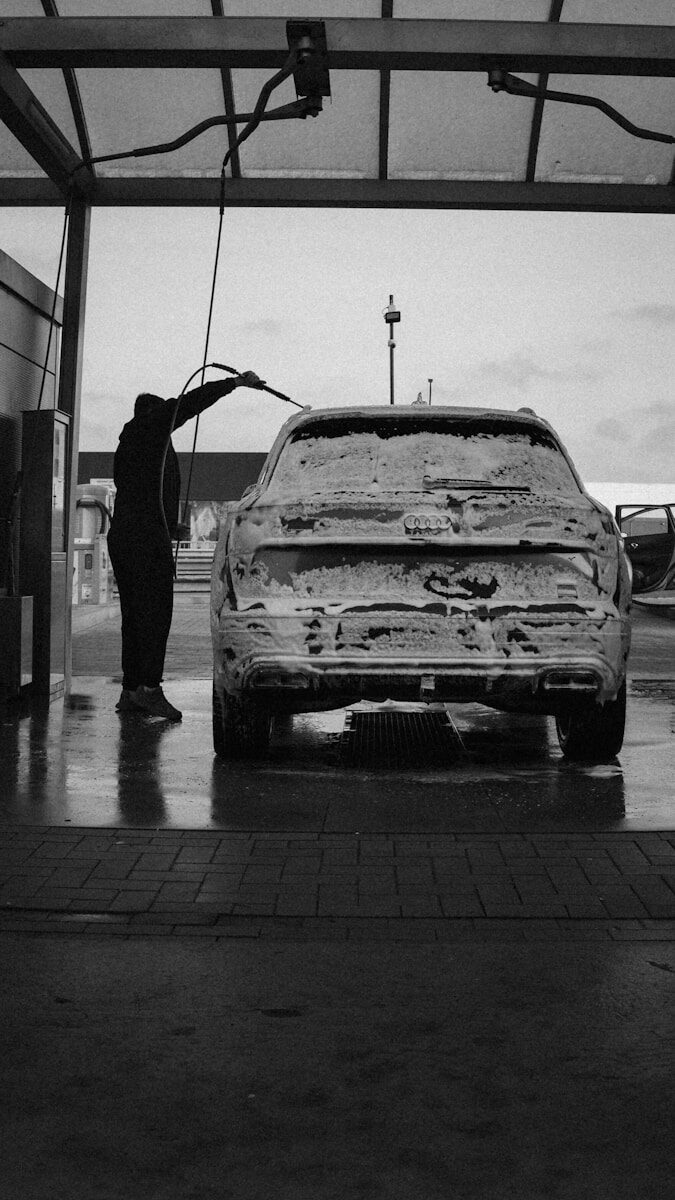 Person washing a car covered in foam