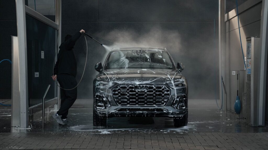 Auto Detailing 101: How to Transform Your Car’s Appearance and Value 1 Person washing a black car with soap and water.