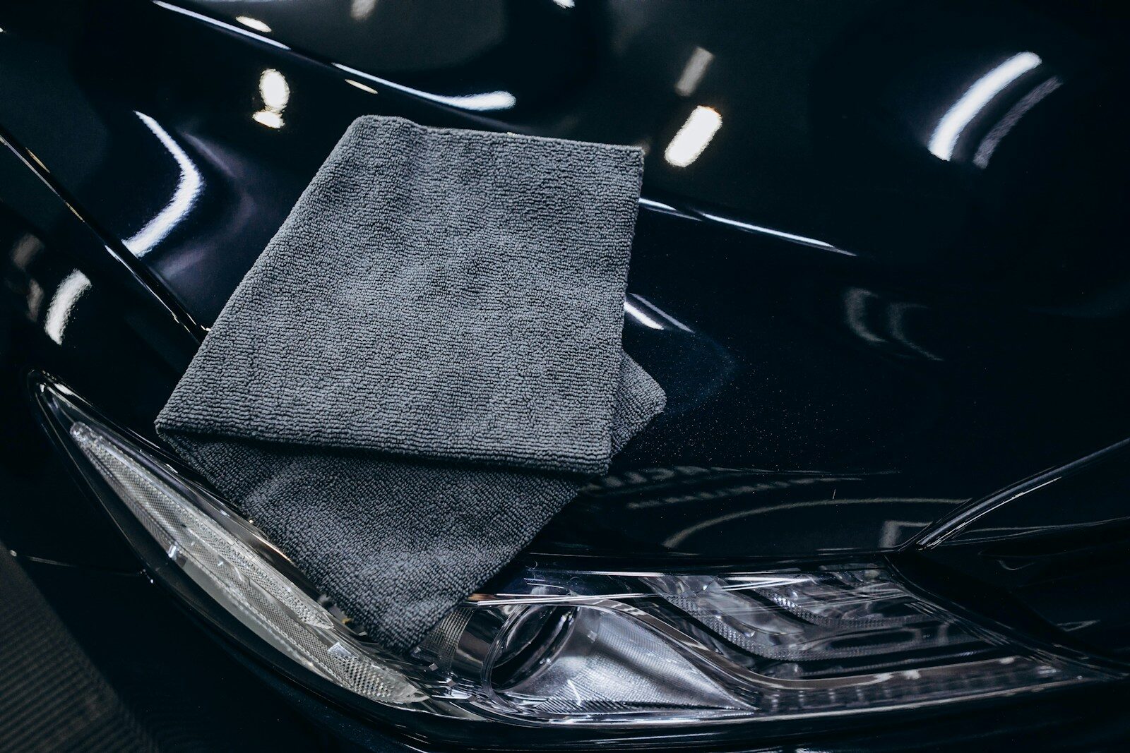Gray microfiber cloth on a black car hood.