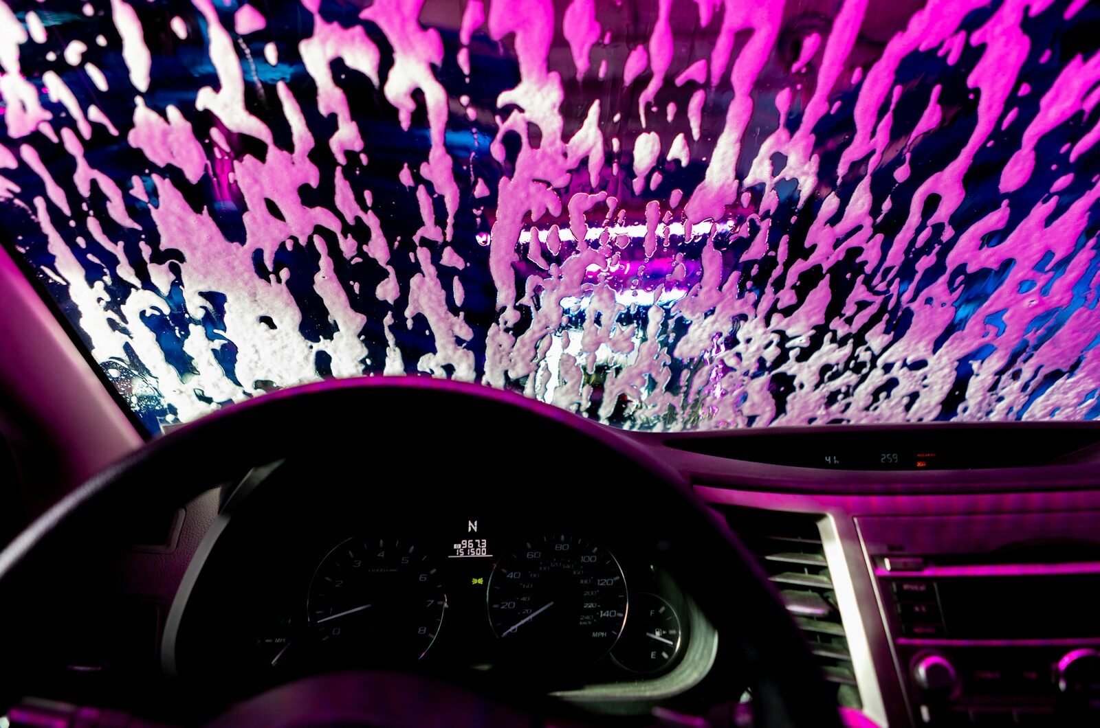 Car interior with pink soap suds on windshield