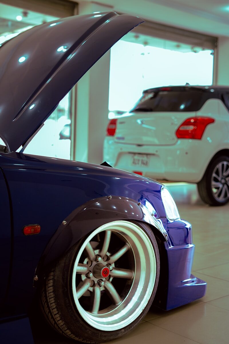 Modified blue car with open hood and custom wheels.