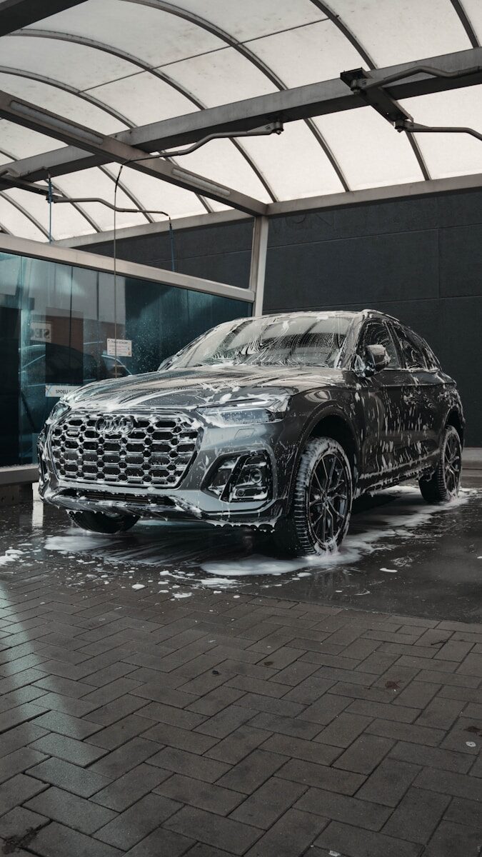 Photo by Avenir Visuals A dark suv covered in soap at a car wash.