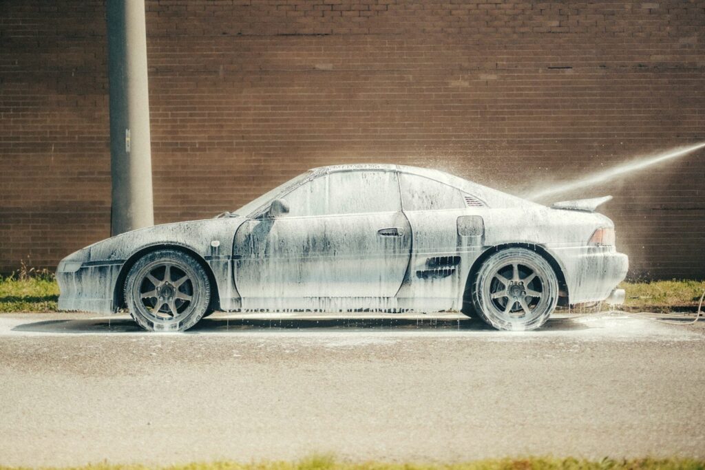 White car being washed with foam and covered in foam.