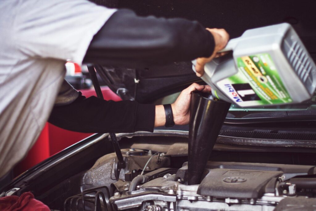 Car Maintenance Checklist: A Simple Guide for Frederick Vehicle Owners 1 man refilling motor oil on car engine bay